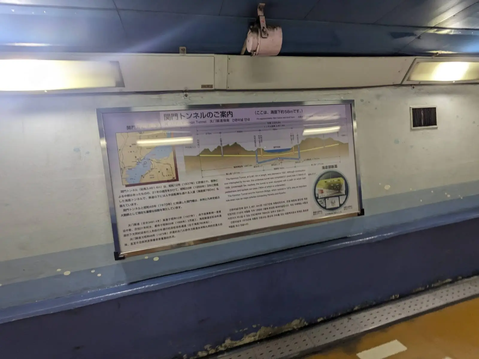 An informational plaque mounted on a tunnel wall showing a map and illustration with Japanese text