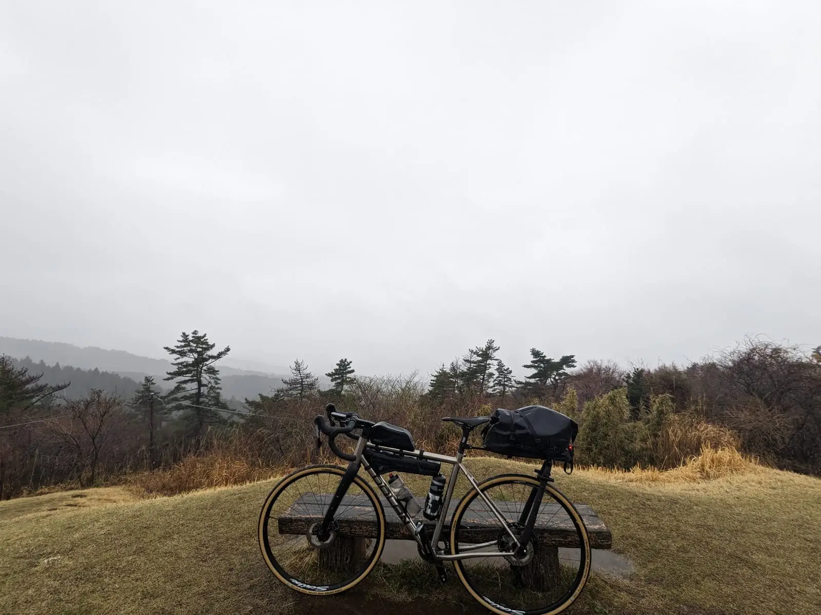 A bike leaning against a railing at a viewpoint, overlooking a valley completely obscured by cloud where Mount Fuji should be