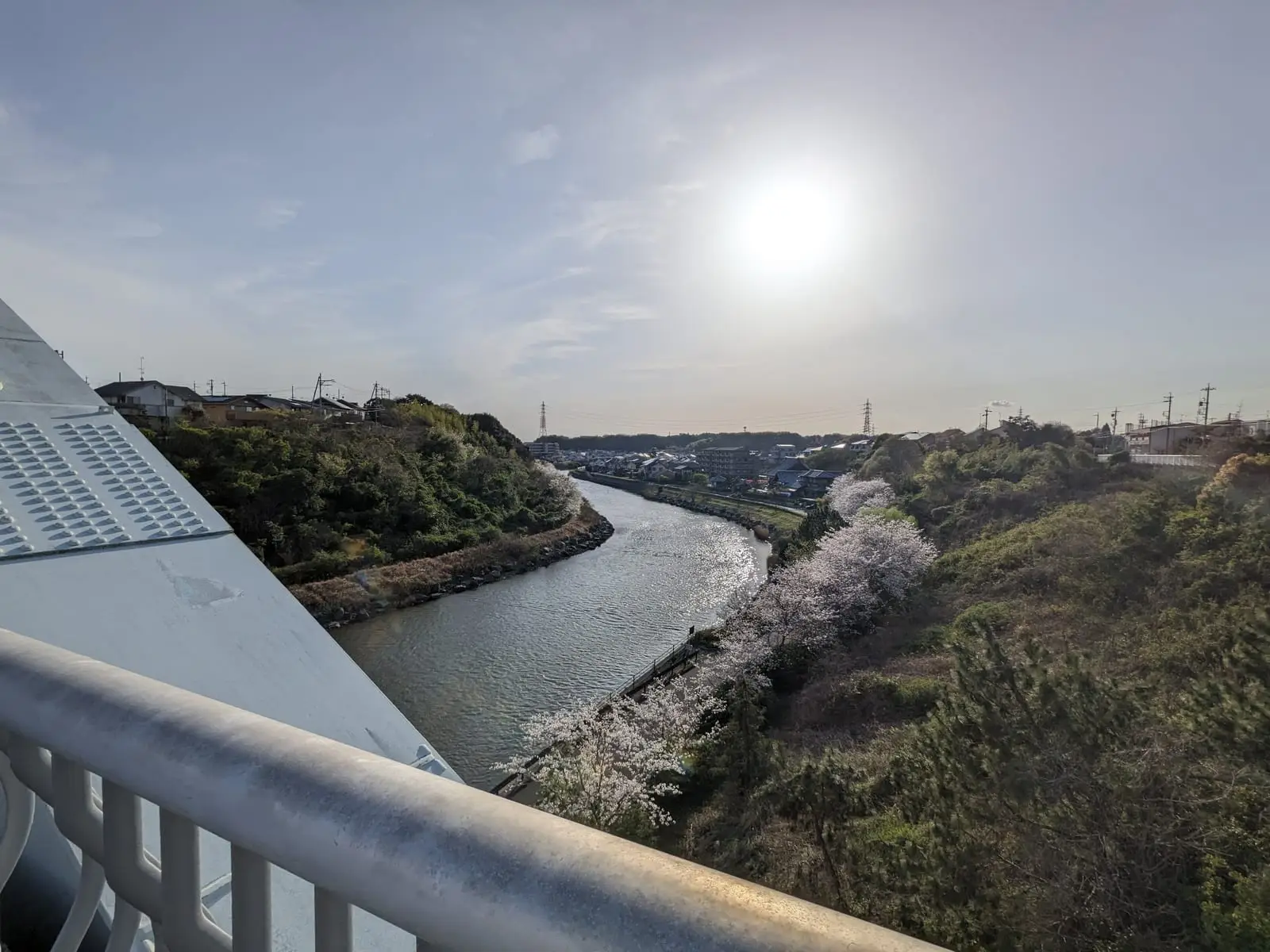 A winding river between hills, seen from a bridge in warm evening light