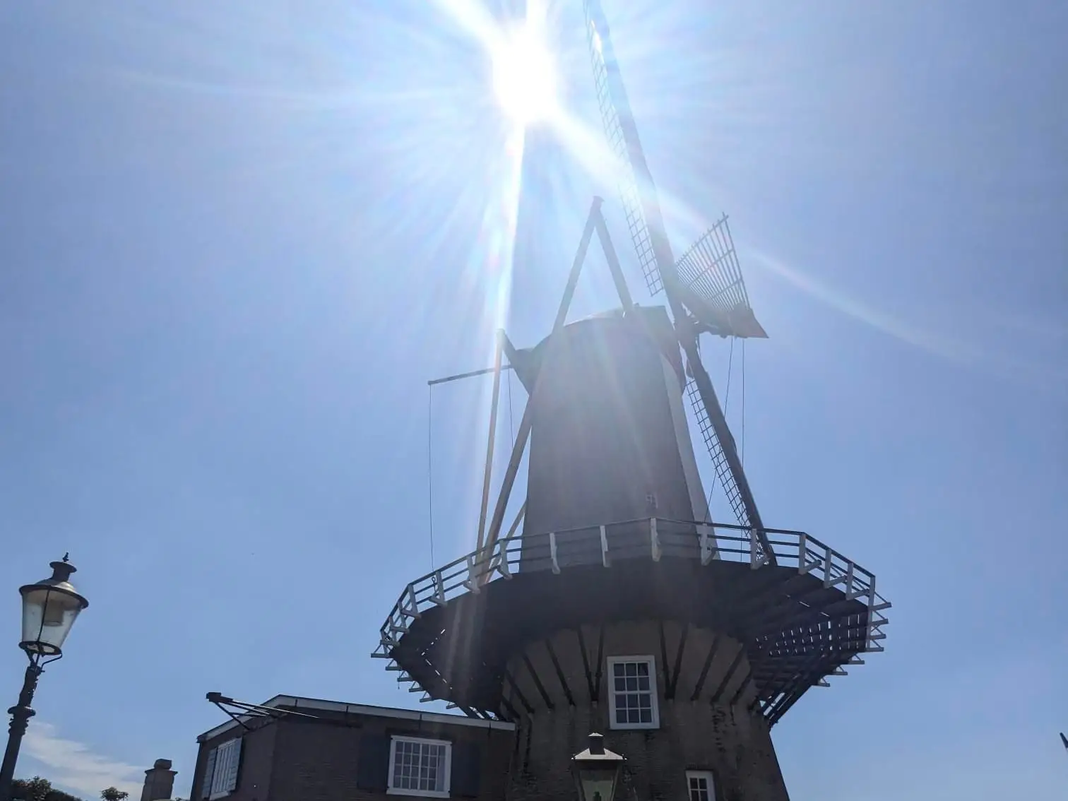A windmill silhouetted against a bright sun and clear blue sky